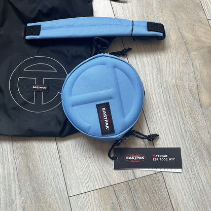 Eastpak x Telfar Circle Blue Shoulder Bag is crafted from polyester tactical canvas in a Cerulean colorway with black-tone hardware. The bag features woven hand straps, a removable and adjustable padded shoulder strap for crossbody or waist wear, and an embossed Telfar logo on the exterior. Released for SS24 on 06/14/2024 with a retail price of $110, the interior includes zip pockets and mesh compartments for organized storage.