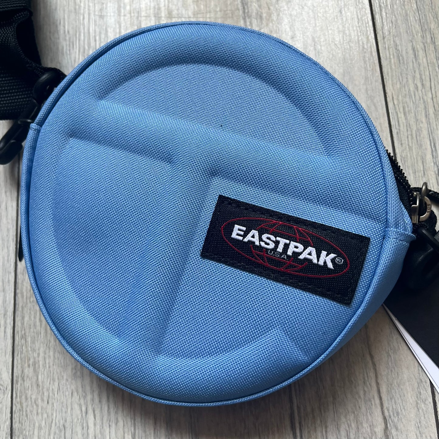 Eastpak x Telfar Circle Blue Shoulder Bag is crafted from polyester tactical canvas in a Cerulean colorway with black-tone hardware. The bag features woven hand straps, a removable and adjustable padded shoulder strap for crossbody or waist wear, and an embossed Telfar logo on the exterior. Released for SS24 on 06/14/2024 with a retail price of $110, the interior includes zip pockets and mesh compartments for organized storage.