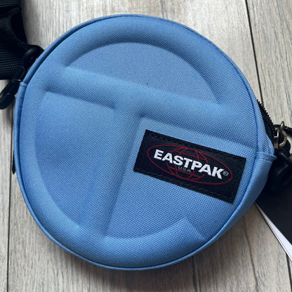 Eastpak x Telfar Circle Blue Shoulder Bag is crafted from polyester tactical canvas in a Cerulean colorway with black-tone hardware. The bag features woven hand straps, a removable and adjustable padded shoulder strap for crossbody or waist wear, and an embossed Telfar logo on the exterior. Released for SS24 on 06/14/2024 with a retail price of $110, the interior includes zip pockets and mesh compartments for organized storage.