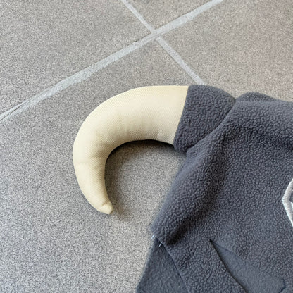 The Elder Scrolls V: Skyrim 2011 Dragonborn Helmet Hat is a grey fleece helmet-style beanie with large cream-colored curved horns and eye openings. The front features an embroidered light grey Skyrim dragon emblem on the forehead. Originally distributed by Bethesda as a promotional item at PAX Prime in 2011.
