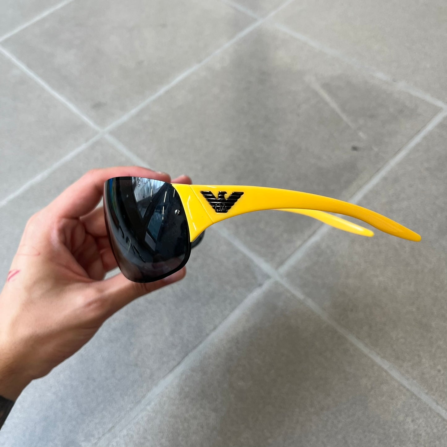 Emporio Armani 2000's Shield Yellow Sunglasses feature a black shield-style front with a single continuous lens and yellow temples. The temples have black Emporio Armani eagle logos, with model EA 9242/S SVG95. Made in Italy and comes with the original red case.

