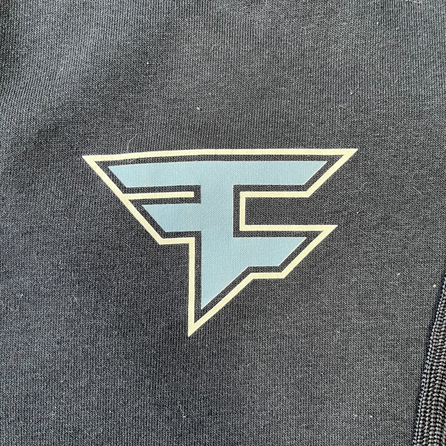 FaZe Clan x Manchester City 2019 Hoodie is an official collaboration combining esports and football culture. Made in Portugal from a 60% cotton and 40% polyester blend, it features the Manchester City club crest on the right chest and the FaZe Clan logo on the left. The back is finished with a large "FAZE CITY" graphic, with ribbed cuffs, a ribbed hem, and a kangaroo pocket.