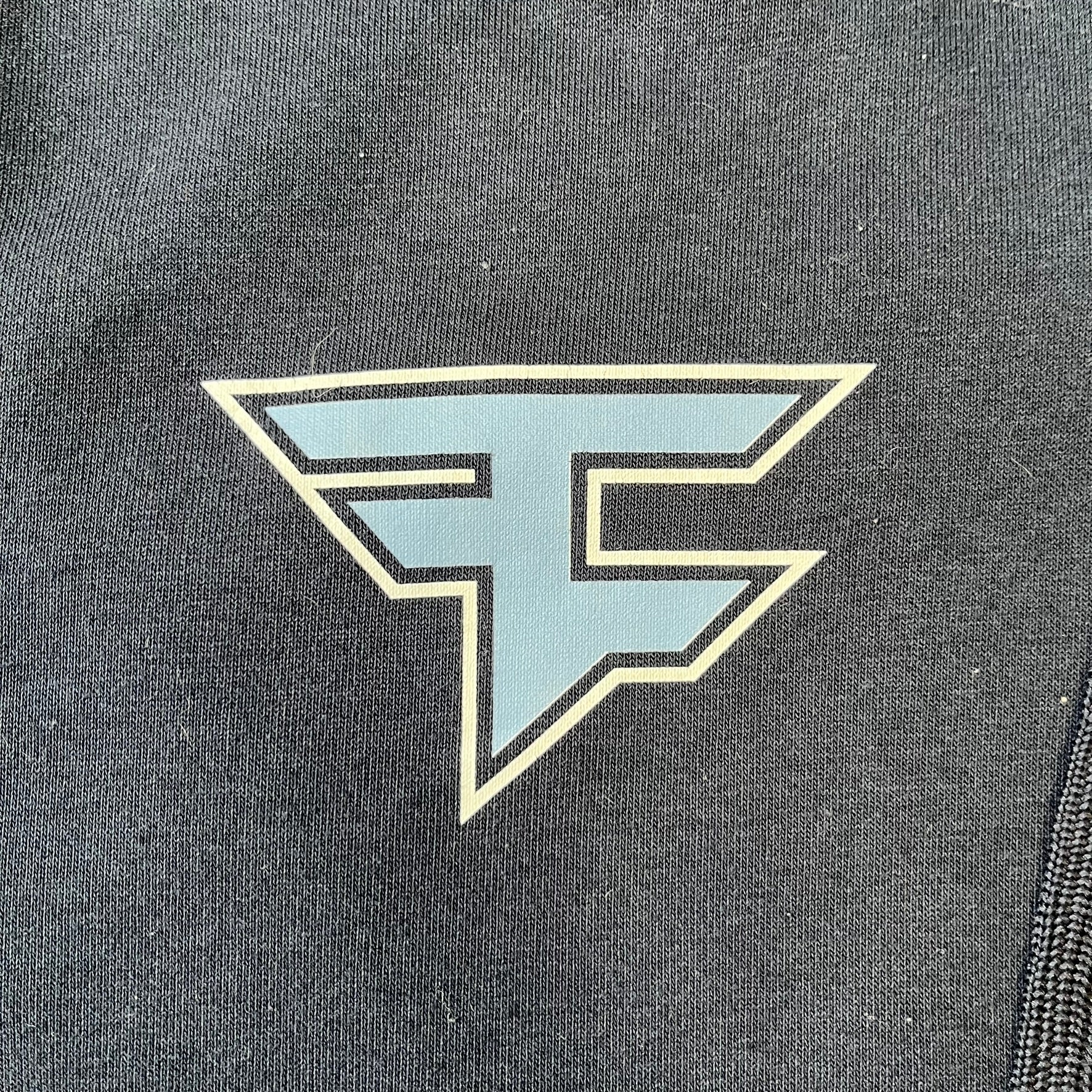 FaZe Clan x Manchester City 2019 Hoodie is an official collaboration combining esports and football culture. Made in Portugal from a 60% cotton and 40% polyester blend, it features the Manchester City club crest on the right chest and the FaZe Clan logo on the left. The back is finished with a large "FAZE CITY" graphic, with ribbed cuffs, a ribbed hem, and a kangaroo pocket.