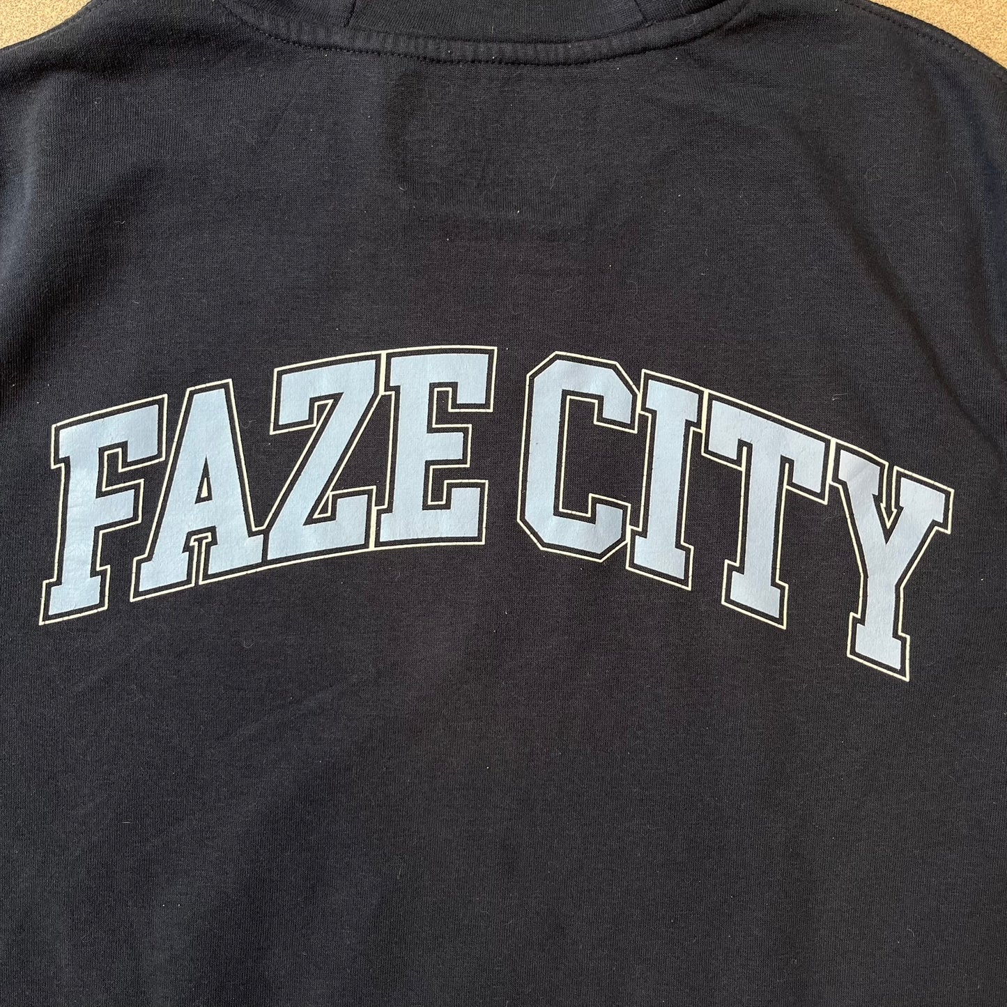 FaZe Clan x Manchester City 2019 Hoodie is an official collaboration combining esports and football culture. Made in Portugal from a 60% cotton and 40% polyester blend, it features the Manchester City club crest on the right chest and the FaZe Clan logo on the left. The back is finished with a large "FAZE CITY" graphic, with ribbed cuffs, a ribbed hem, and a kangaroo pocket.