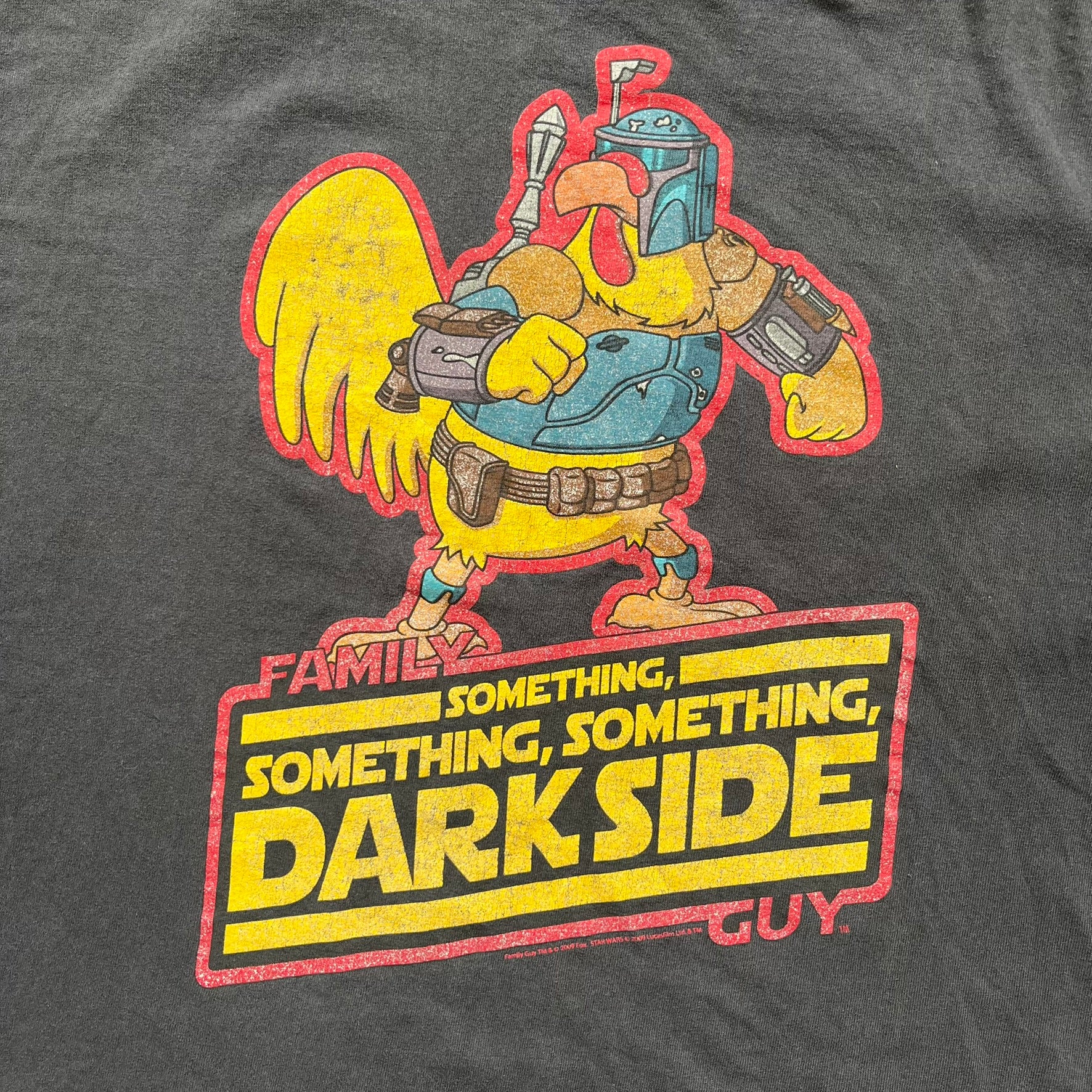 Family Guy 2009 Star Wars "Something Darkside" Tee is a washed black T-shirt made on a Delta Pro Weight blank. The front features Ernie the Giant Chicken dressed as Boba Fett above yellow Star Wars-style “Something, Something, Something, Dark Side” text with a red Family Guy outline surrounding the graphic. Small 2009 licensing details are printed below the design.