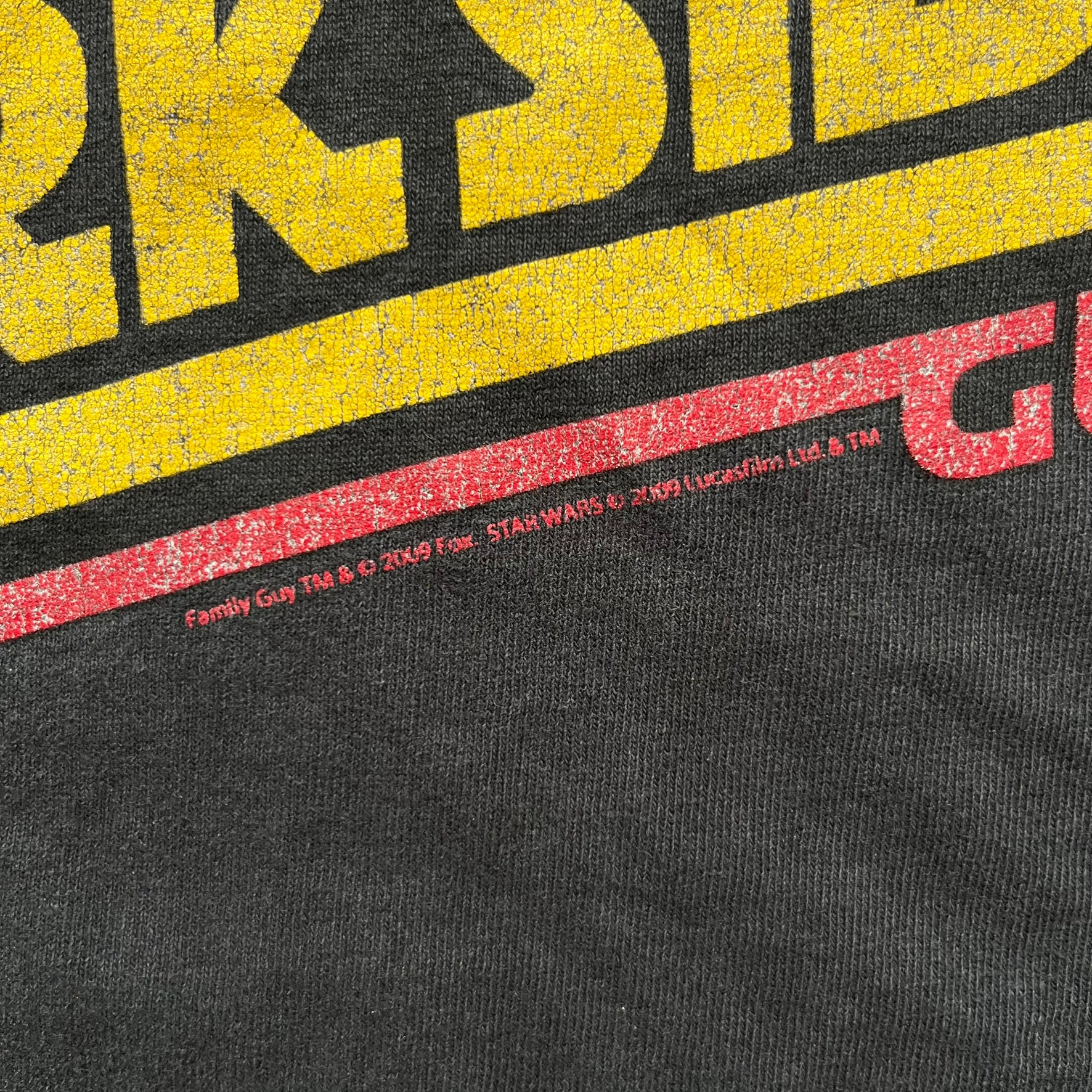 Family Guy 2009 Star Wars "Something Darkside" Tee is a washed black T-shirt made on a Delta Pro Weight blank. The front features Ernie the Giant Chicken dressed as Boba Fett above yellow Star Wars-style “Something, Something, Something, Dark Side” text with a red Family Guy outline surrounding the graphic. Small 2009 licensing details are printed below the design.