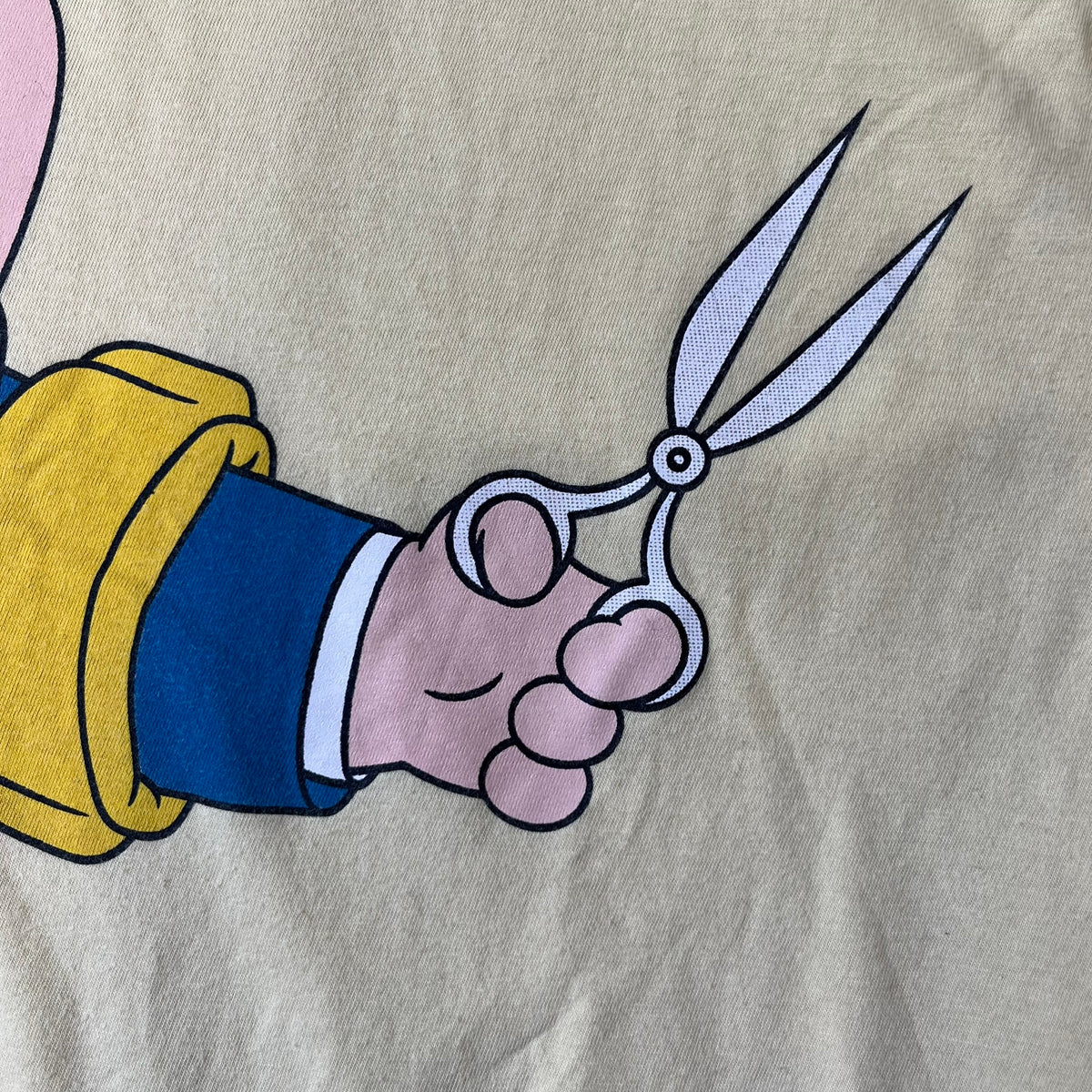 Family Guy 2012 Peter Griffin #1 Dad Tee features a yellow T-shirt with a front graphic of Peter Griffin wearing a helmet and elbow and knee protectors while running with a pair of scissors. A “#1 Dad” text is printed underneath the graphic. Includes a 2012 licensed neck tag.
