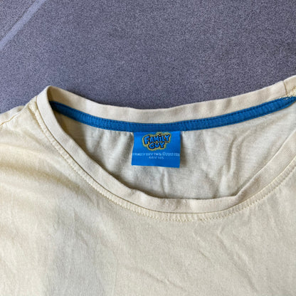 Family Guy 2012 Peter Griffin #1 Dad Tee features a yellow T-shirt with a front graphic of Peter Griffin wearing a helmet and elbow and knee protectors while running with a pair of scissors. A “#1 Dad” text is printed underneath the graphic. Includes a 2012 licensed neck tag.
