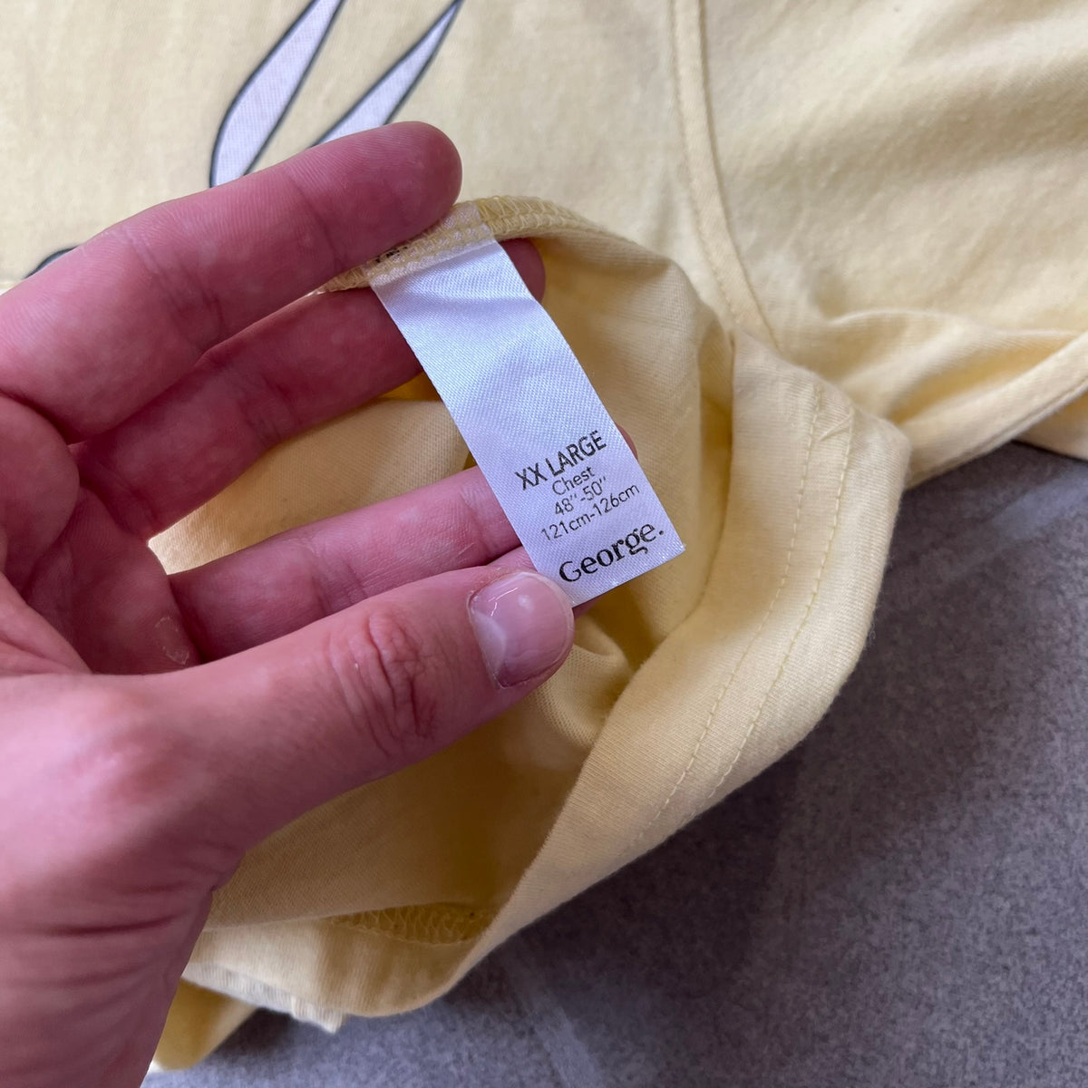 Family Guy 2012 Peter Griffin #1 Dad Tee features a yellow T-shirt with a front graphic of Peter Griffin wearing a helmet and elbow and knee protectors while running with a pair of scissors. A “#1 Dad” text is printed underneath the graphic. Includes a 2012 licensed neck tag.
