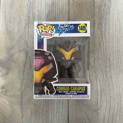 Funko Pop! Movies: Blue Beetle Conrad Carapax #1405 is a 2023 vinyl figure from the DC Blue Beetle (2023) movie line. It depicts Conrad Carapax in his armored design with a color scheme of deep maroon, bright yellow, and metallic accents. The figure is part of the standard 4-inch POP! vinyl series and features detailed sculpting based on the film character