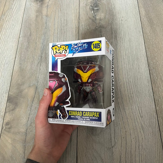 Funko Pop! Movies: Blue Beetle Conrad Carapax #1405 is a 2023 vinyl figure from the DC Blue Beetle (2023) movie line. It depicts Conrad Carapax in his armored design with a color scheme of deep maroon, bright yellow, and metallic accents. The figure is part of the standard 4-inch POP! vinyl series and features detailed sculpting based on the film character