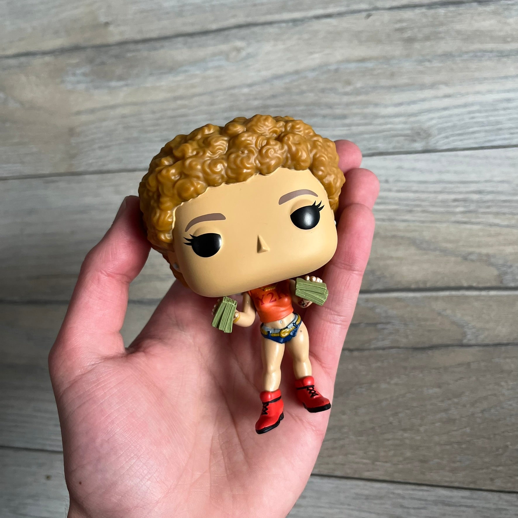 Funko Pop! Rocks Ice Spice (Classic Y2K!) #448 Figure is a vinyl collectible released in 2025 as part of the Funko Pop! Rocks music series. The figure represents Ice Spice wearing her orange Y2K! era outfit and holding stacks of money in both hands. The figure follows the standard Funko Pop! stylized design and was released on May 8, 2025 under the Pop! Rocks line.