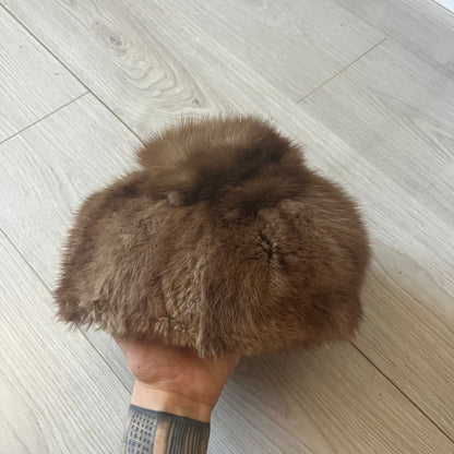 Brown fur winter hat in a compact beret-style shape, resembling a classic pillbox design. Soft and cozy, it provides warmth while maintaining a sleek, minimalist silhouette. A subtle yet stylish accessory for cold-weather wear.