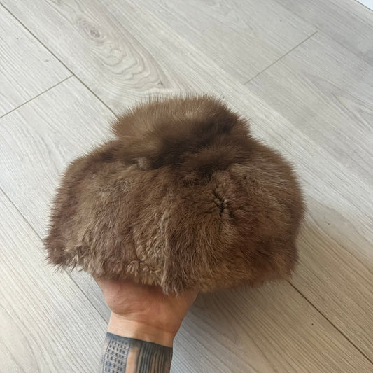 Brown fur winter hat in a compact beret-style shape, resembling a classic pillbox design. Soft and cozy, it provides warmth while maintaining a sleek, minimalist silhouette. A subtle yet stylish accessory for cold-weather wear.