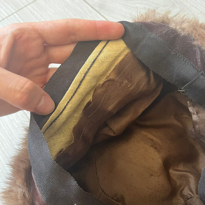 Brown fur winter hat in a compact beret-style shape, resembling a classic pillbox design. Soft and cozy, it provides warmth while maintaining a sleek, minimalist silhouette. A subtle yet stylish accessory for cold-weather wear.