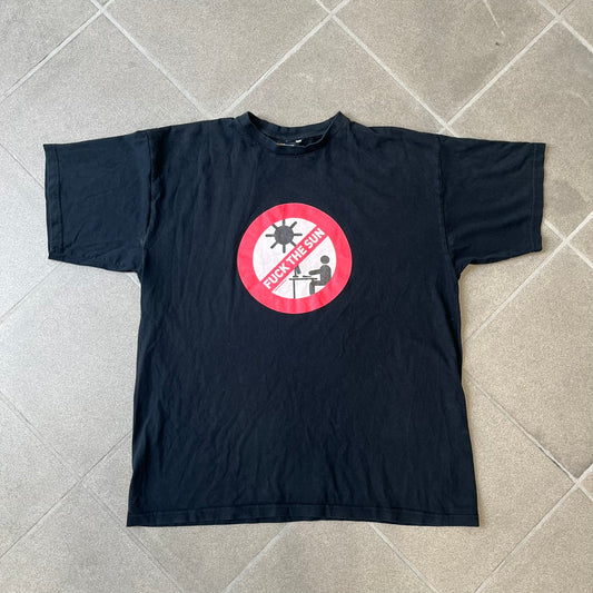 GamersWear 2010's Fuck The Sun Black Tee features a black 100% cotton T-shirt with a road sign-style graphic on the front. The graphic shows a black figure sitting at a computer beneath a black sun, surrounded by a white background and red outline. A red line crosses the design with white “Fuck The Sun” text, along with small red GamersWear branding.
