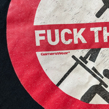 GamersWear 2010's Fuck The Sun Black Tee features a black 100% cotton T-shirt with a road sign-style graphic on the front. The graphic shows a black figure sitting at a computer beneath a black sun, surrounded by a white background and red outline. A red line crosses the design with white “Fuck The Sun” text, along with small red GamersWear branding.

