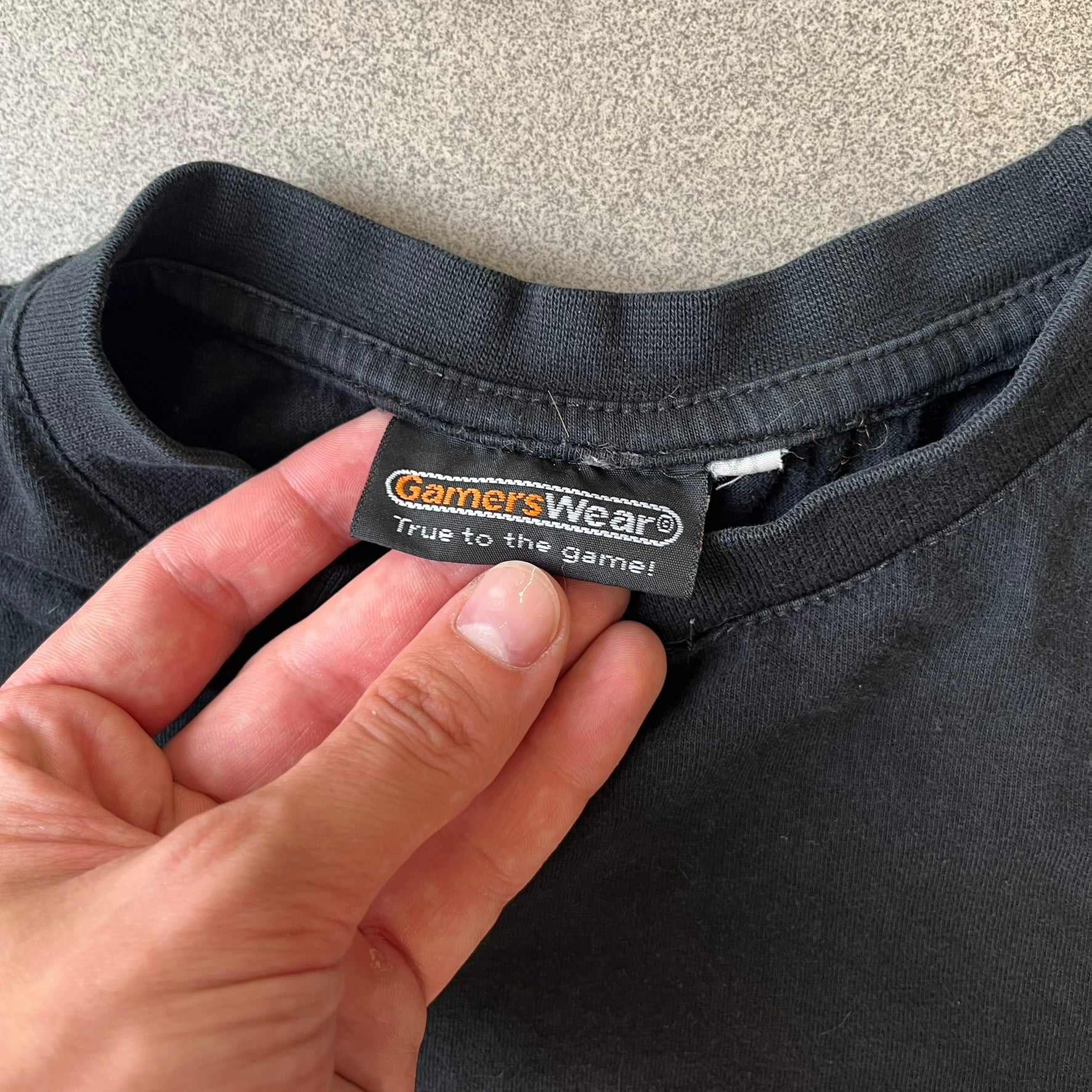 GamersWear 2010's Fuck The Sun Black Tee features a black 100% cotton T-shirt with a road sign-style graphic on the front. The graphic shows a black figure sitting at a computer beneath a black sun, surrounded by a white background and red outline. A red line crosses the design with white “Fuck The Sun” text, along with small red GamersWear branding.
