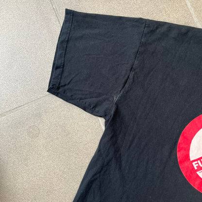 GamersWear 2010's Fuck The Sun Black Tee features a black 100% cotton T-shirt with a road sign-style graphic on the front. The graphic shows a black figure sitting at a computer beneath a black sun, surrounded by a white background and red outline. A red line crosses the design with white “Fuck The Sun” text, along with small red GamersWear branding.
