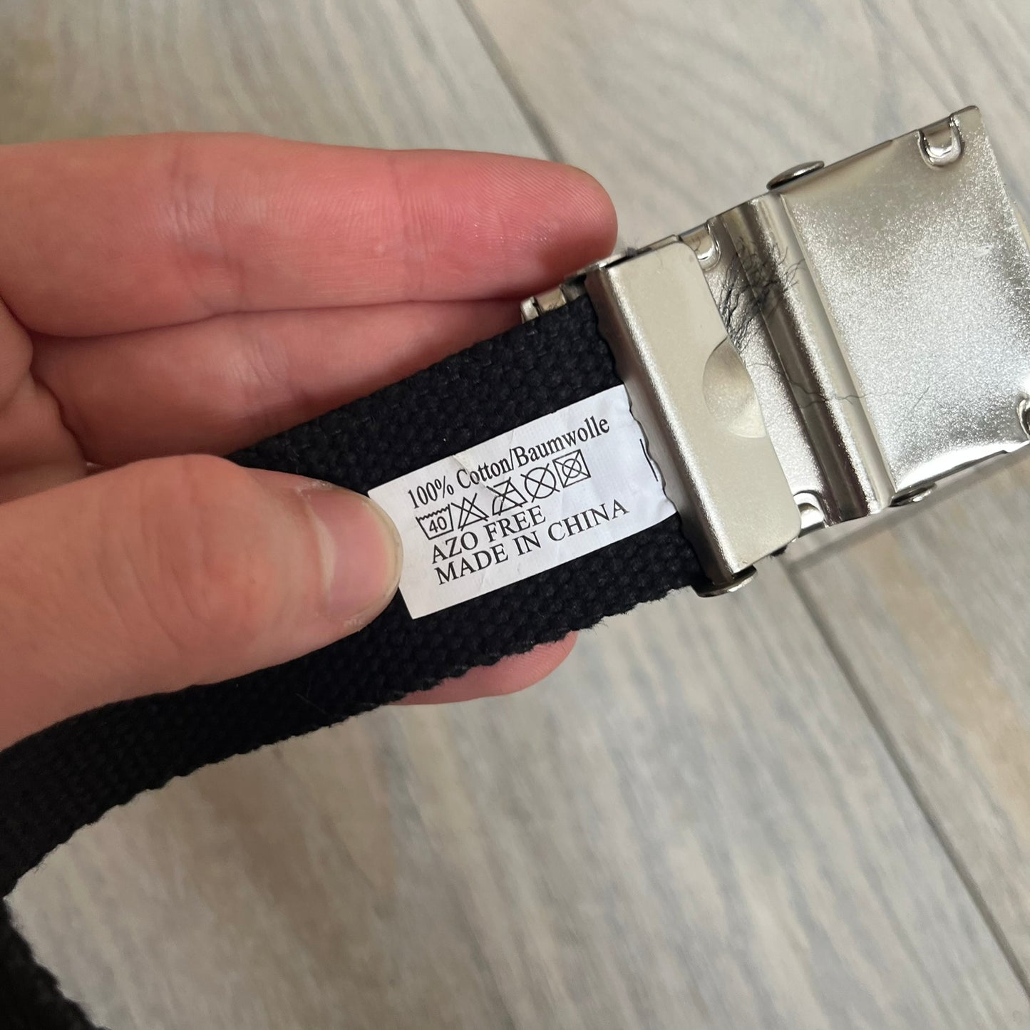 Gamerswear Counter-Strike 2016 Black Belt is a black cotton belt with an adjustable fit and a metal tip featuring a cutout Gamerswear logo. The buckle showcases an armed character in a silver finish, framed by blue enamel on the left side and red enamel on the right. The central figure is highlighted with a raised silver design and matching silver border detailing.