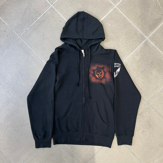 Gears of War 3 Marcus Fenix 2010 Promo Hoodie is a black zip-up hoodie with a dark Crimson Omen logo in orange tones on the left upper chest and a bloody Delta-One logo on one sleeve. The back features a large Marcus Fenix graphic with “Gears of War 3” text below it and a small 2010 Epic Games licensing mark.