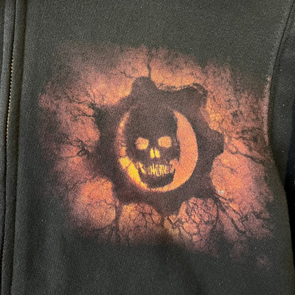 Gears of War 3 Marcus Fenix 2010 Promo Hoodie is a black zip-up hoodie with a dark Crimson Omen logo in orange tones on the left upper chest and a bloody Delta-One logo on one sleeve. The back features a large Marcus Fenix graphic with “Gears of War 3” text below it and a small 2010 Epic Games licensing mark.