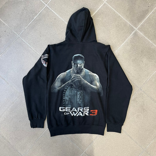 Gears of War 3 Marcus Fenix 2010 Promo Hoodie is a black zip-up hoodie with a dark Crimson Omen logo in orange tones on the left upper chest and a bloody Delta-One logo on one sleeve. The back features a large Marcus Fenix graphic with “Gears of War 3” text below it and a small 2010 Epic Games licensing mark.
