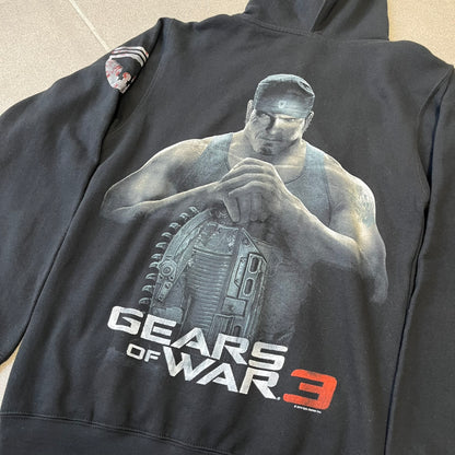 Gears of War 3 Marcus Fenix 2010 Promo Hoodie is a black zip-up hoodie with a dark Crimson Omen logo in orange tones on the left upper chest and a bloody Delta-One logo on one sleeve. The back features a large Marcus Fenix graphic with “Gears of War 3” text below it and a small 2010 Epic Games licensing mark.