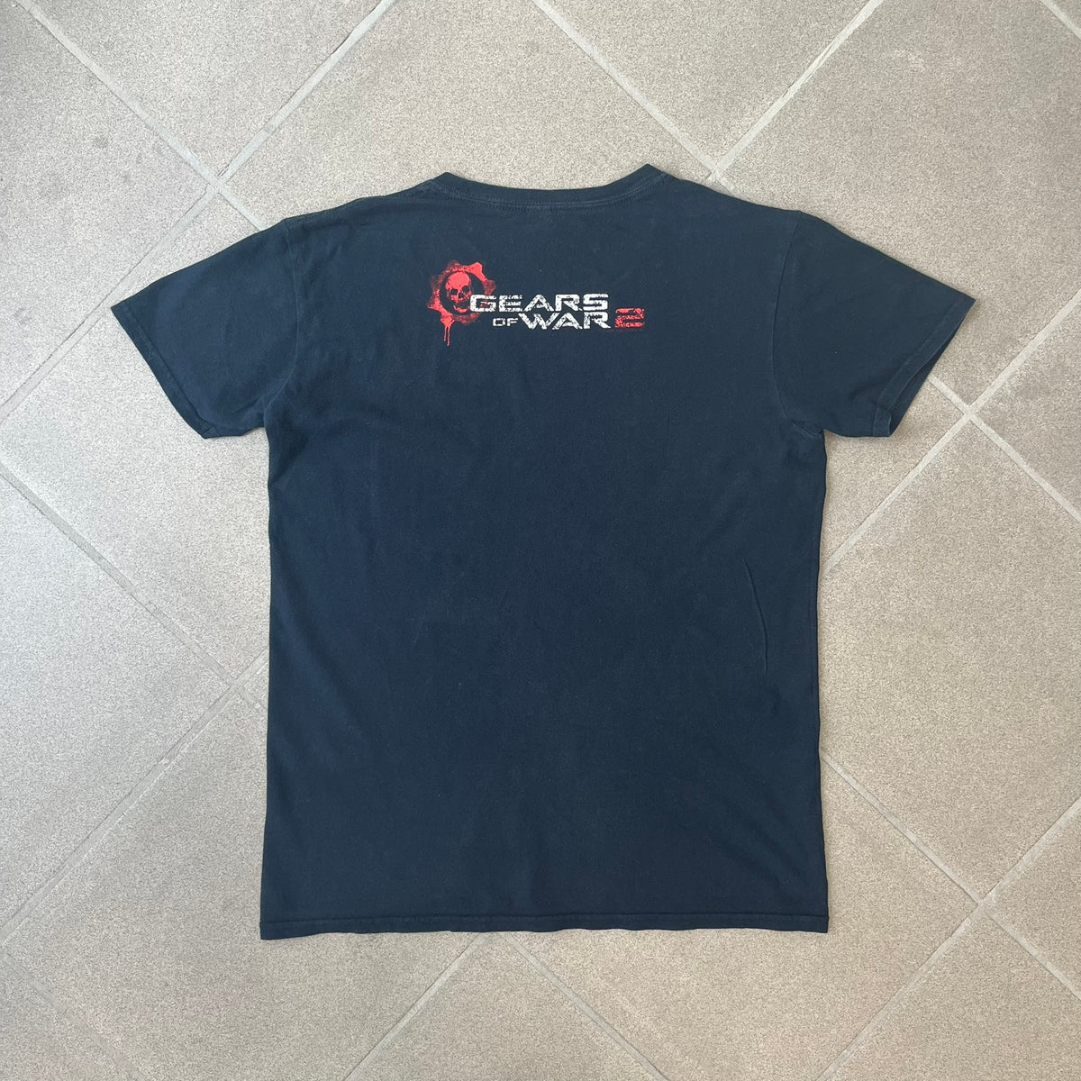 Gears of War 2 2008 Red Lancer Tee is a black, 100% cotton T-shirt featuring a large red Lancer graphic on the front alongside small white "Gears of War 2" text. The upper back displays the GOW2 skull logo with 2008 licensing below.