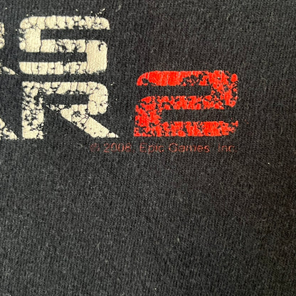 Gears of War 2 2008 Red Lancer Tee is a black, 100% cotton T-shirt featuring a large red Lancer graphic on the front alongside small white "Gears of War 2" text. The upper back displays the GOW2 skull logo with 2008 licensing below.