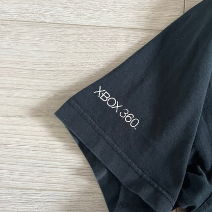 Black Gears of War Tee for Xbox 360 with a small red skull front logo on the chest and white Xbox 360 logo on the sleeve. The back features a full-color cover graphic with Marcus Fenix and branding of the game and Epic Games. Xbox tagged on the side, wash tag is faded.