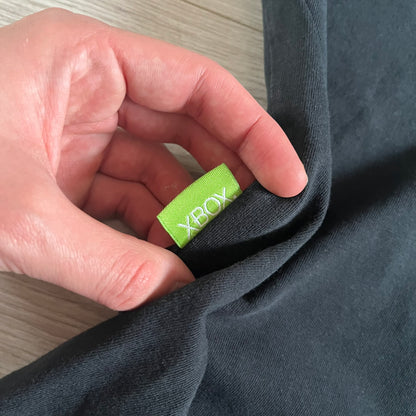 Black Gears of War Tee for Xbox 360 with a small red skull front logo on the chest and white Xbox 360 logo on the sleeve. The back features a full-color cover graphic with Marcus Fenix and branding of the game and Epic Games. Xbox tagged on the side, wash tag is faded.