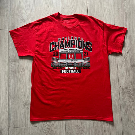 Red t-shirt with 'National Champions' graphic on a wooden floor