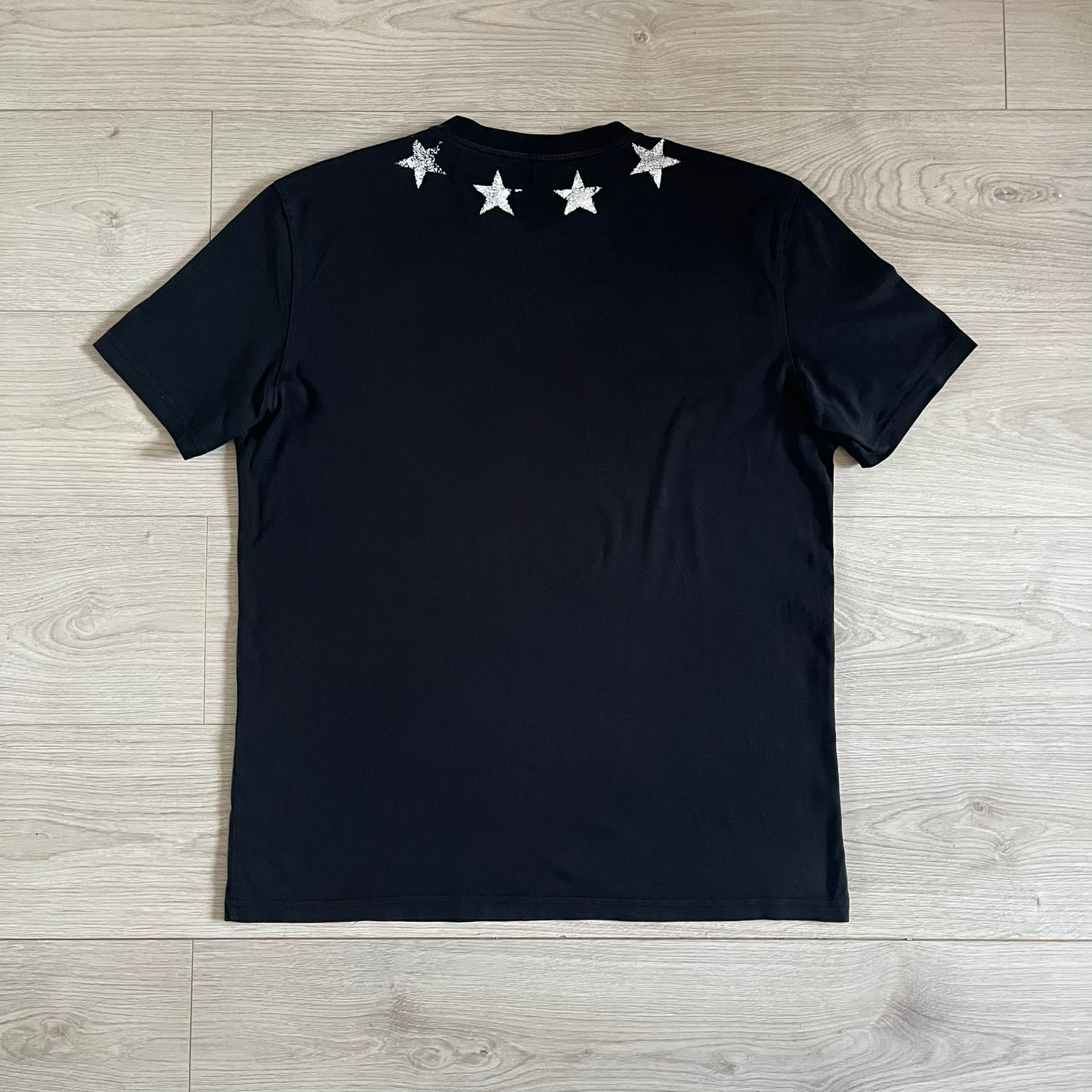 This Givenchy Distressed Black Stars Tee features the label’s iconic star motif from the FW18 season, with five stars across the front collar and four at the back. Crafted in Portugal from 100% cotton, it offers a slim fit and a soft, ribbed crewneck finish. A sought-after Givenchy stars shirt, and yes the distressed stars are intentional, not due to wear.