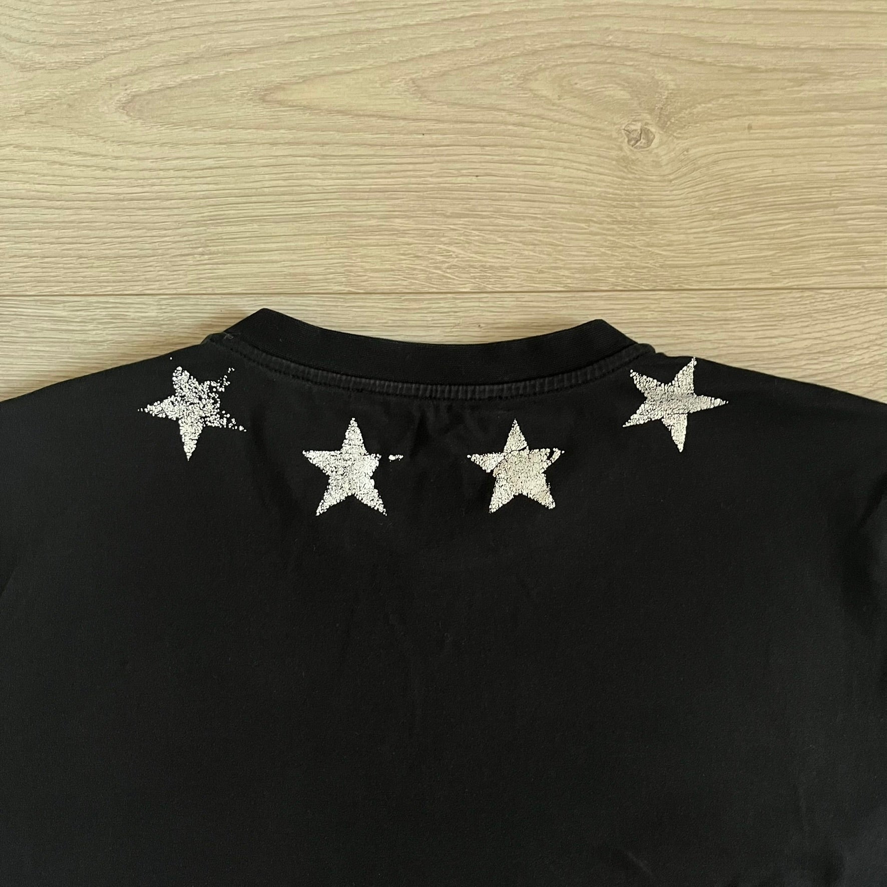 This Givenchy Distressed Black Stars Tee features the label’s iconic star motif from the FW18 season, with five stars across the front collar and four at the back. Crafted in Portugal from 100% cotton, it offers a slim fit and a soft, ribbed crewneck finish. A sought-after Givenchy stars shirt, and yes the distressed stars are intentional, not due to wear.