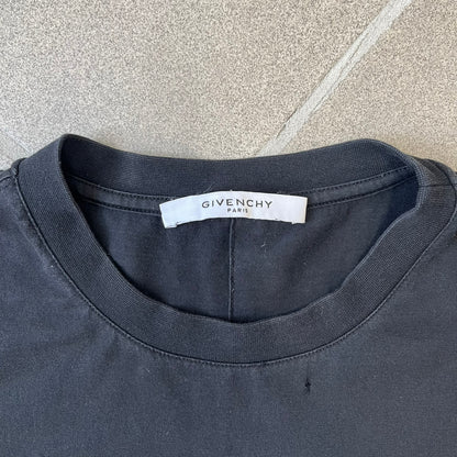 Givenchy Distressed Logo Paris Tee is a black T-shirt made from 100% cotton in Portugal, featuring white "GIVENCHY" text on the chest with "PARIS" printed below it. The shirt is finished with an all-over factory-distressed design, with holes intentionally placed across both the front and back.