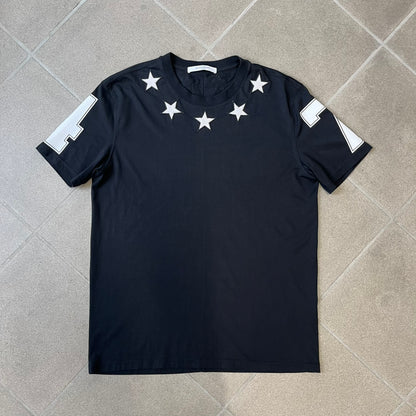 Givenchy 2017 Black Star Patch 4-7 Tee is a black, Cuban-fit T-shirt made from 100% cotton, featuring fuzzy white star patches trimming the collar on both the front and back. White "4" and "7" numbering is printed on the sleeves.