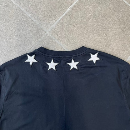 Givenchy 2017 Black Star Patch 4-7 Tee is a black, Cuban-fit T-shirt made from 100% cotton, featuring fuzzy white star patches trimming the collar on both the front and back. White "4" and "7" numbering is printed on the sleeves.