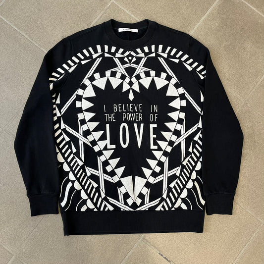 Givenchy FW16 "I Believe in the Power of Love" Crewneck is a black crewneck made from 100% cotton, featuring a white graphic heart built from varying patterns that grow from small to large, with "I Believe in the Power of Love" text placed at its center.&nbsp;