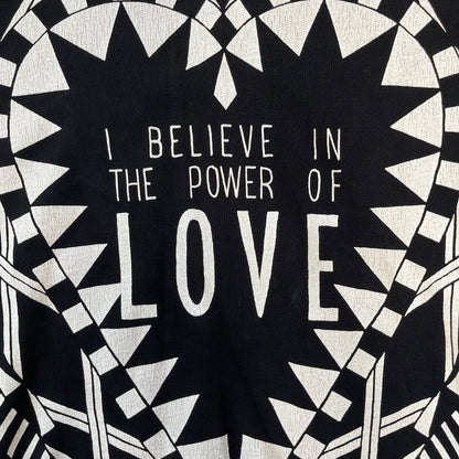 Givenchy FW16 "I Believe in the Power of Love" Crewneck is a black crewneck made from 100% cotton, featuring a white graphic heart built from varying patterns that grow from small to large, with "I Believe in the Power of Love" text placed at its center.&nbsp;