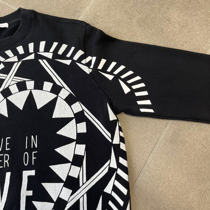 Givenchy FW16 "I Believe in the Power of Love" Crewneck is a black crewneck made from 100% cotton, featuring a white graphic heart built from varying patterns that grow from small to large, with "I Believe in the Power of Love" text placed at its center.&nbsp;