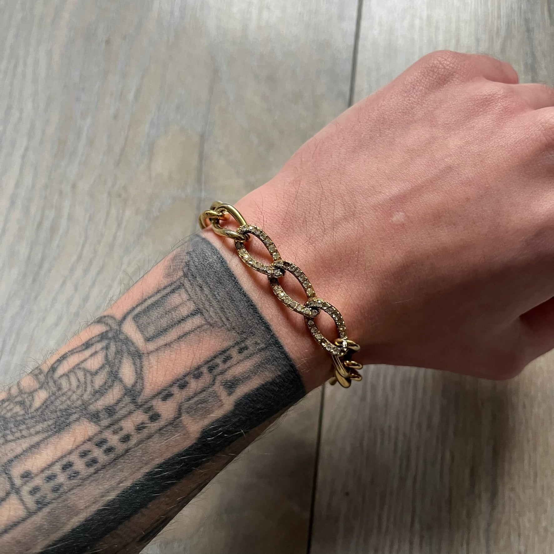 The Givenchy Gold-Tone Crystal Pavé Link Bracelet features a gold-tone Pavé Link chain with larger circular end links connecting to the clasp. The 3 middle links have embedded crystals. The foldover clasp is stamped Givenchy Paris New York. Vintage piece with a consistent gold-tone finish.