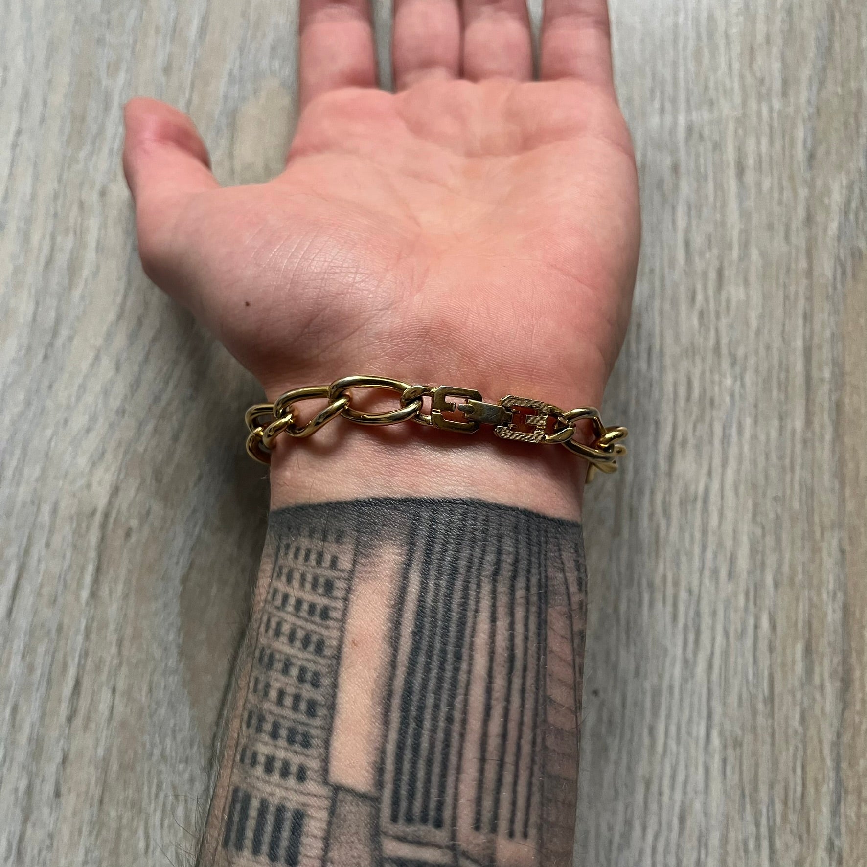 The Givenchy Gold-Tone Crystal Pavé Link Bracelet features a gold-tone Pavé Link chain with larger circular end links connecting to the clasp. The 3 middle links have embedded crystals. The foldover clasp is stamped Givenchy Paris New York. Vintage piece with a consistent gold-tone finish.