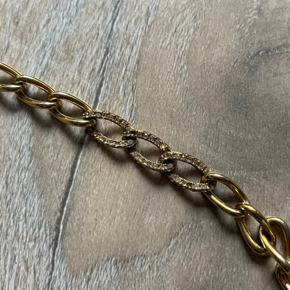 The Givenchy Gold-Tone Crystal Pavé Link Bracelet features a gold-tone Pavé Link chain with larger circular end links connecting to the clasp. The 3 middle links have embedded crystals. The foldover clasp is stamped Givenchy Paris New York. Vintage piece with a consistent gold-tone finish.