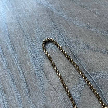 The Givenchy Gold-Tone Vintage Rope Bracelet features a thin gold-tone rope-style chain with larger circular end links shaped like the Givenchy “G” connecting to the clasp. The foldover clasp is oversized compared to the chain and is stamped Givenchy Paris New York. Vintage piece with a uniform gold-tone finish.