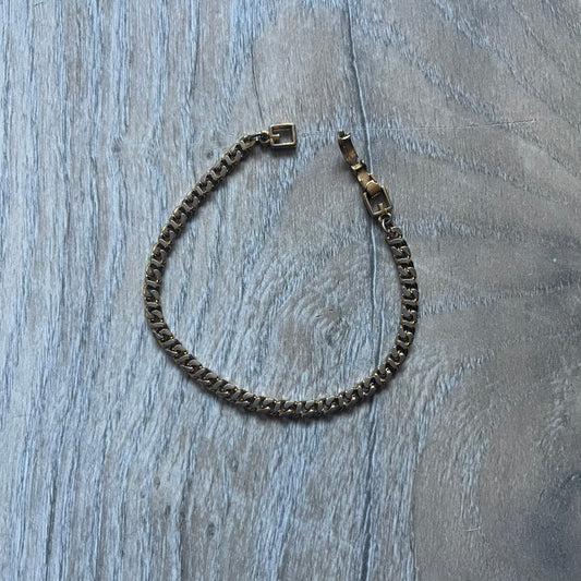 The Givenchy Gold-Tone Vintage Chain Bracelet features a thin gold-tone link chain with larger circular end links shaped like the Givenchy “G” connecting to the clasp. The foldover clasp is branded Givenchy Paris New York and is slightly oversized compared to the rest of the chain.