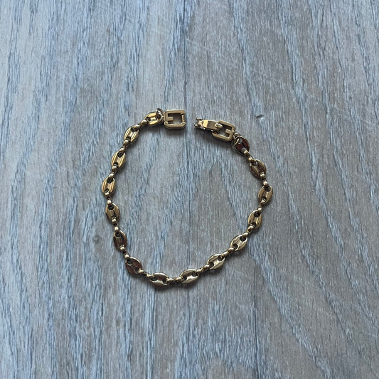 The Givenchy Gold-Tone Vintage Mariner Bracelet features a thin gold-tone mariner-style chain with larger circular end links connecting to the clasp. The foldover clasp is stamped Givenchy Paris New York and is oversized compared to the chain. Vintage piece with a consistent gold-tone finish.