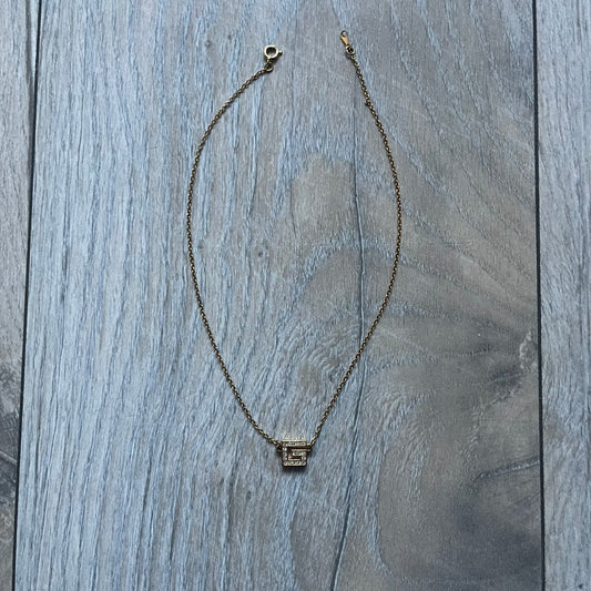 The Givenchy Gold-Tone Vintage Pendant Necklace features a thin gold-tone chain with a central “G” logo pendant embellished with rhinestones. The foldover clasp is stamped Givenchy Paris New York, completing this vintage piece.