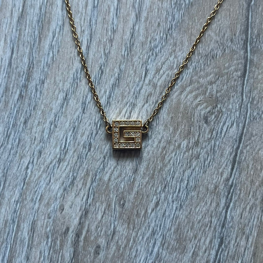 The Givenchy Gold-Tone Vintage Pendant Necklace features a thin gold-tone chain with a central “G” logo pendant embellished with rhinestones. The foldover clasp is stamped Givenchy Paris New York, completing this vintage piece.