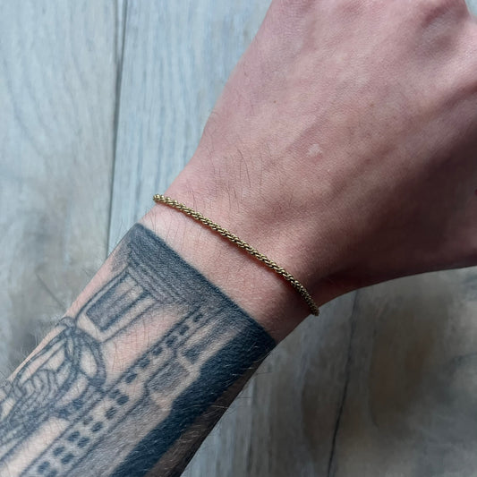 The Givenchy Gold-Tone Vintage Rope Bracelet features a thin gold-tone rope-style chain with larger circular end links shaped like the Givenchy “G” connecting to the clasp. The foldover clasp is oversized compared to the chain and is stamped Givenchy Paris New York. Vintage piece with a uniform gold-tone finish.
